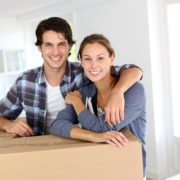 Smiling couple leaning on boxes in new home